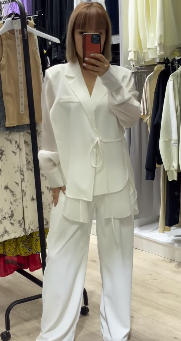 Асимметриялуу көйнөк жана галстук менен ак түстөгү аялдардын шым костюму