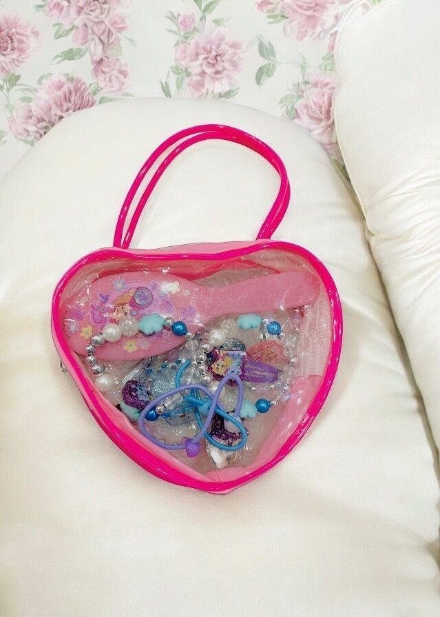 Pink bag with hair accessories and jewelry for kids.