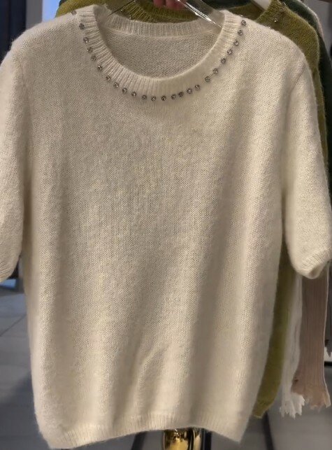 Свитер бежевого цвета с коротким рукавом, горловина украшена стразами