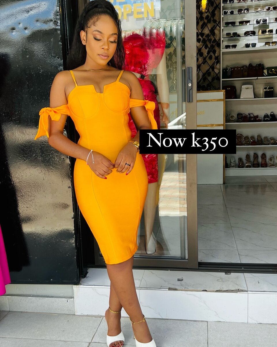 A form-fitting yellow knee-length dress with open shoulders