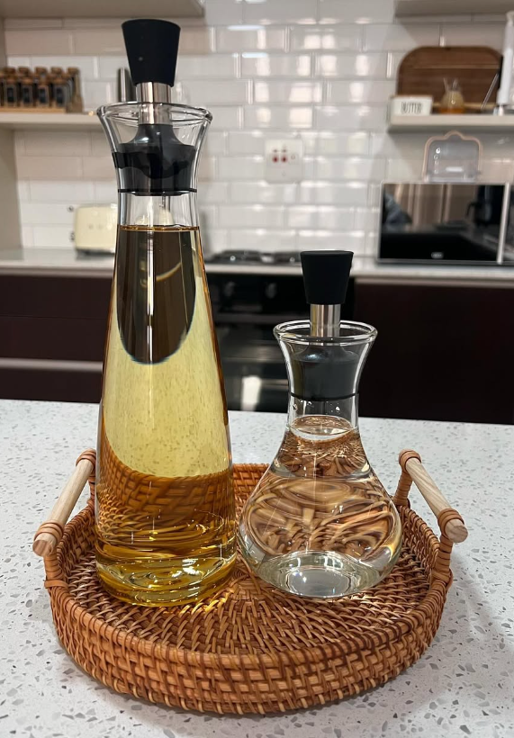 A set of glass bottles for oil and vinegar with dispensers, on a wicker tray