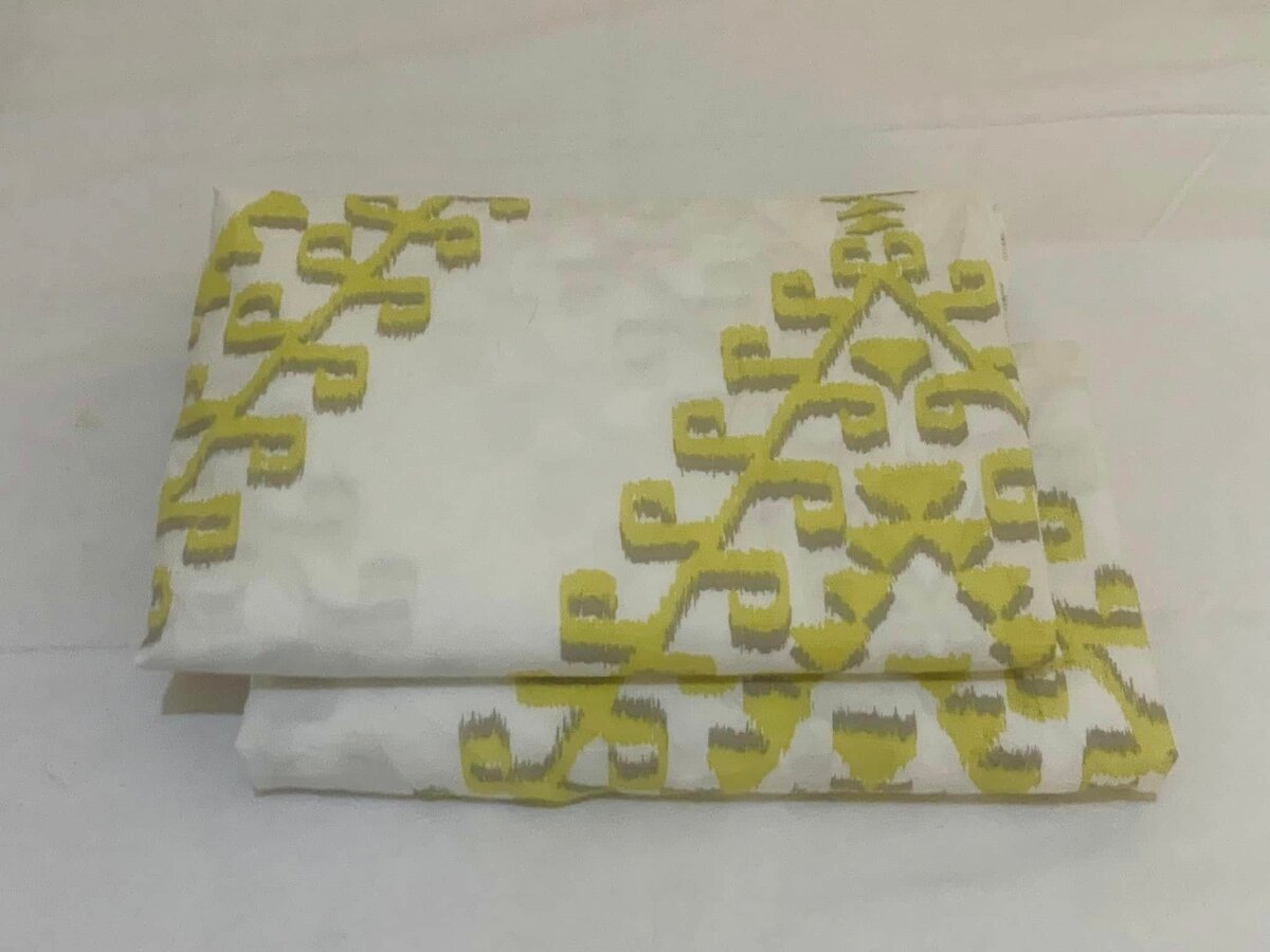 The bed linen is white with a yellow ethnic pattern.