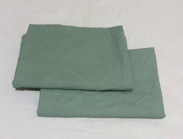 A light green textile product,sheets or pillowcases, folded on a flat surface.