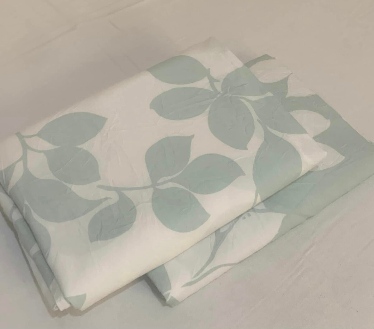 A sheet with a print of green leaves on a white background